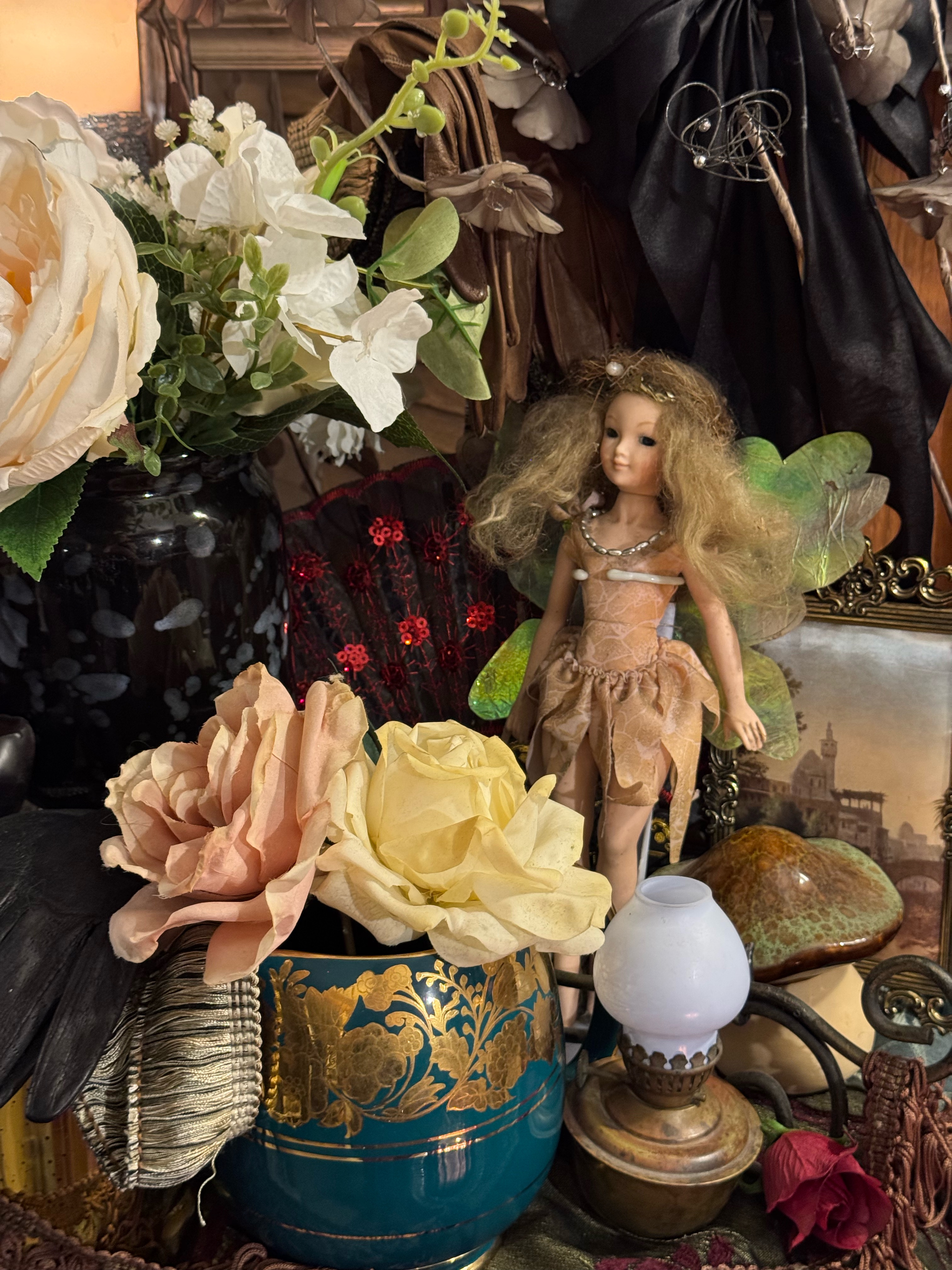 Owner-created Fairy Whimsy styling study with a fairy figure, layered florals, teal-and-gold vessel, framed artwork and vintage detail